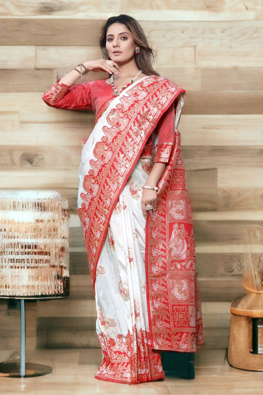 Woman wearing a white saree with red border against a wooden background
