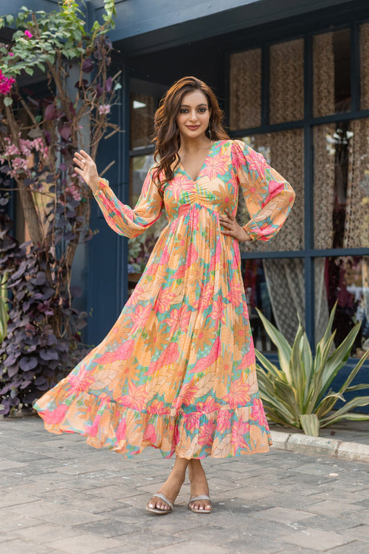 Smiling woman wearing a flowy long sleeve v-neck maxi dress with a pastel orange and pink floral print and tiered ruffles
