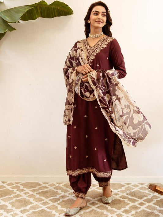 Woman wearing a burgundy embroidered kurta suit with a floral print dupatta and salwar pants
Smiling woman wearing a long sleeve burgundy kurta with gold embroidery, a floral print dupatta, and matching salwar pants