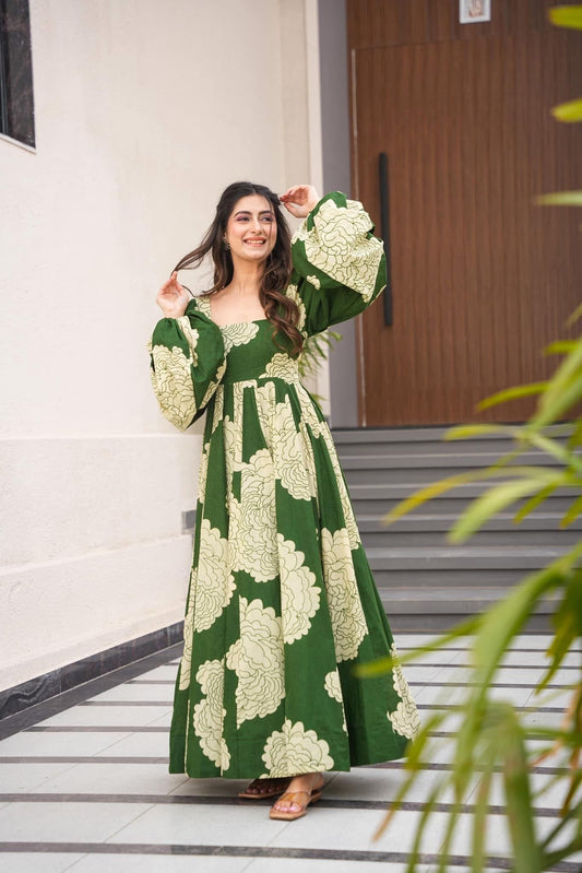 Woman wearing a green floral print long frock with umbrella sleeves
Smiling woman wearing a long green maxi dress with a cream floral print and voluminous umbrella sleeves