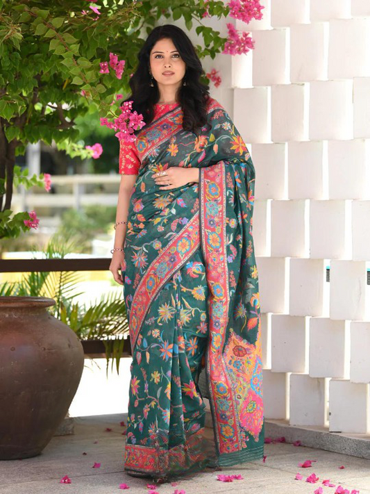 Woman wearing a green saree with floral patterns in an outdoor setting.