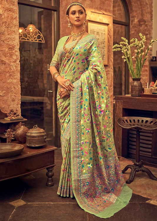 Woman in a traditional saree standing in an indoor setting with decorative elements.