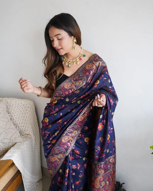 Woman wearing a colorful saree with a patterned design, sitting on a chair.