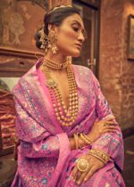 Woman in a pink traditional outfit with gold jewelry in an indoor setting
