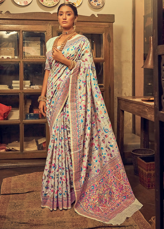 Woman in a traditional saree standing in an indoor setting with decorative elements.