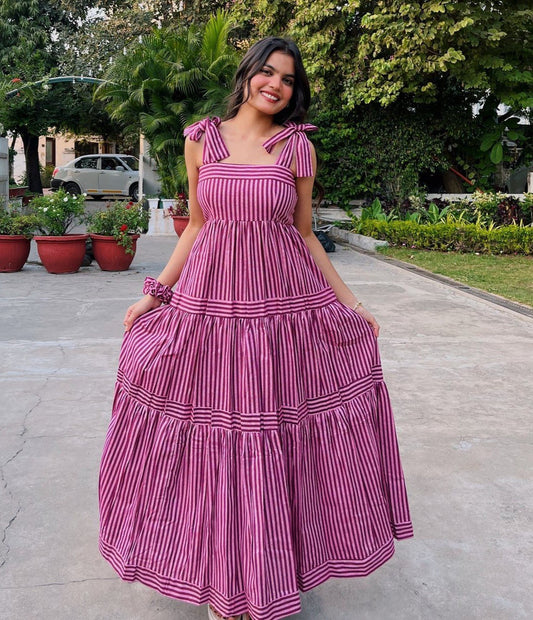 Woman wearing a pink and maroon striped tiered maxi dress with tie shoulders